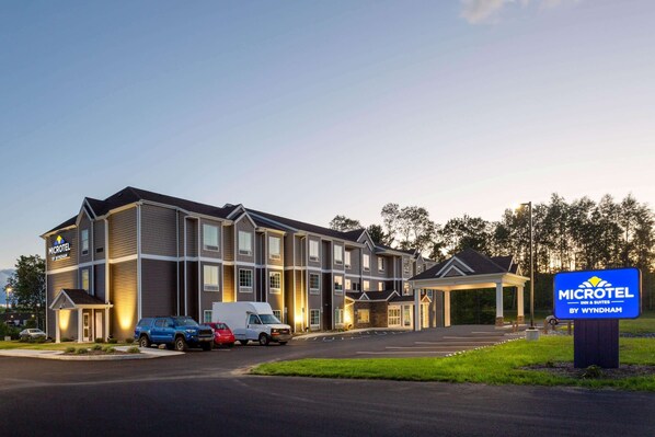Un bâtiment de la chaîne Microtel Inn & Suites, avec un parking, une allée couverte et un panneau indicateur.