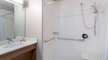 Un baño moderno con lavamanos blanco, espejo y zona de ducha.
