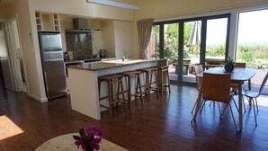 Una cocina moderna con una isla central, taburetes de bar y un comedor con mesa y sillas.