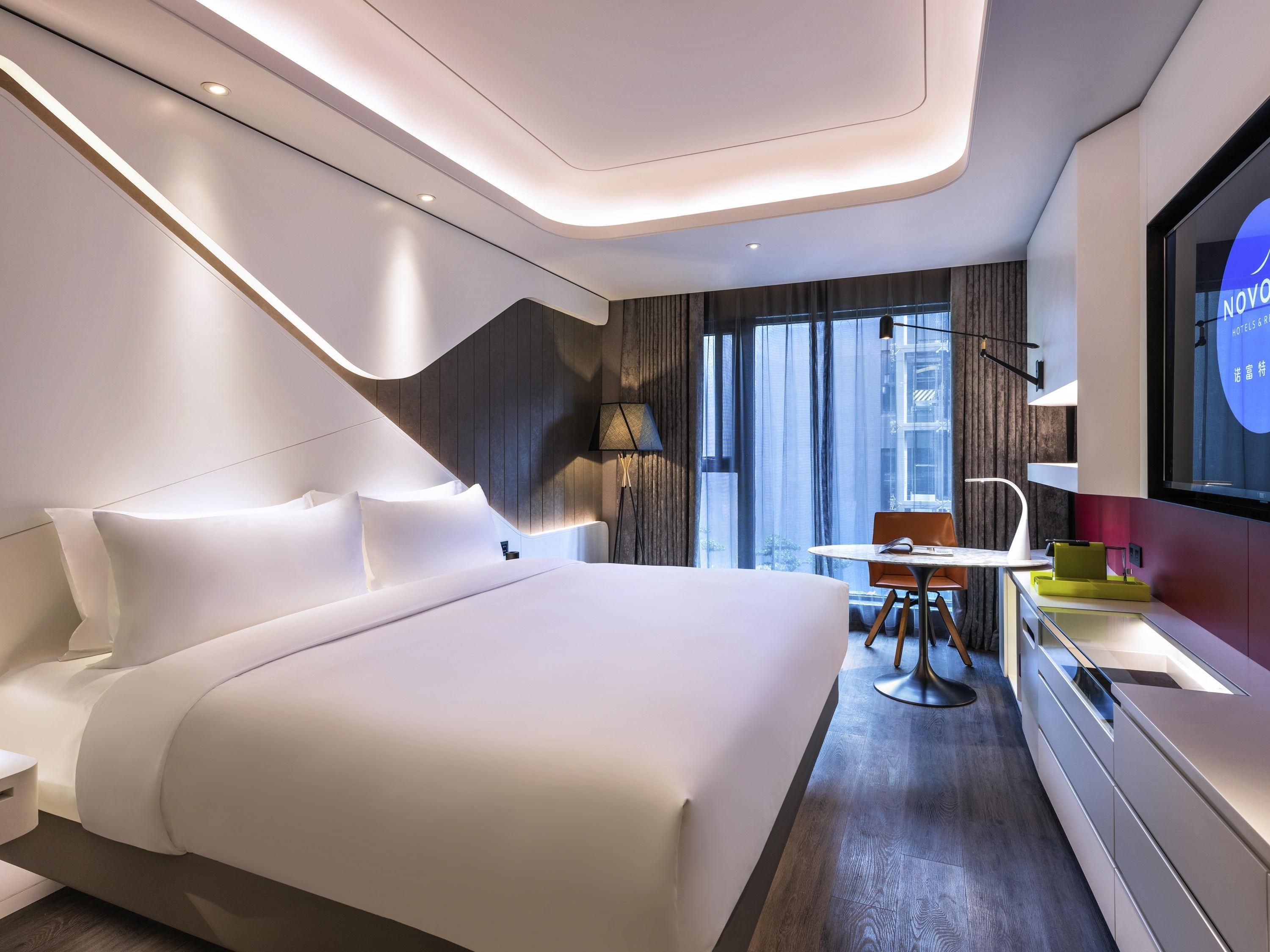 Una camera d'albergo moderna con un letto grande, una scrivania e una televisione.