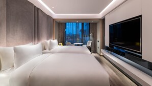 Une chambre d’hôtel moderne dotée d’un grand lit, d’un téléviseur à écran plat, d’une petite table ronde et d’un coin salon avec des fauteuils.