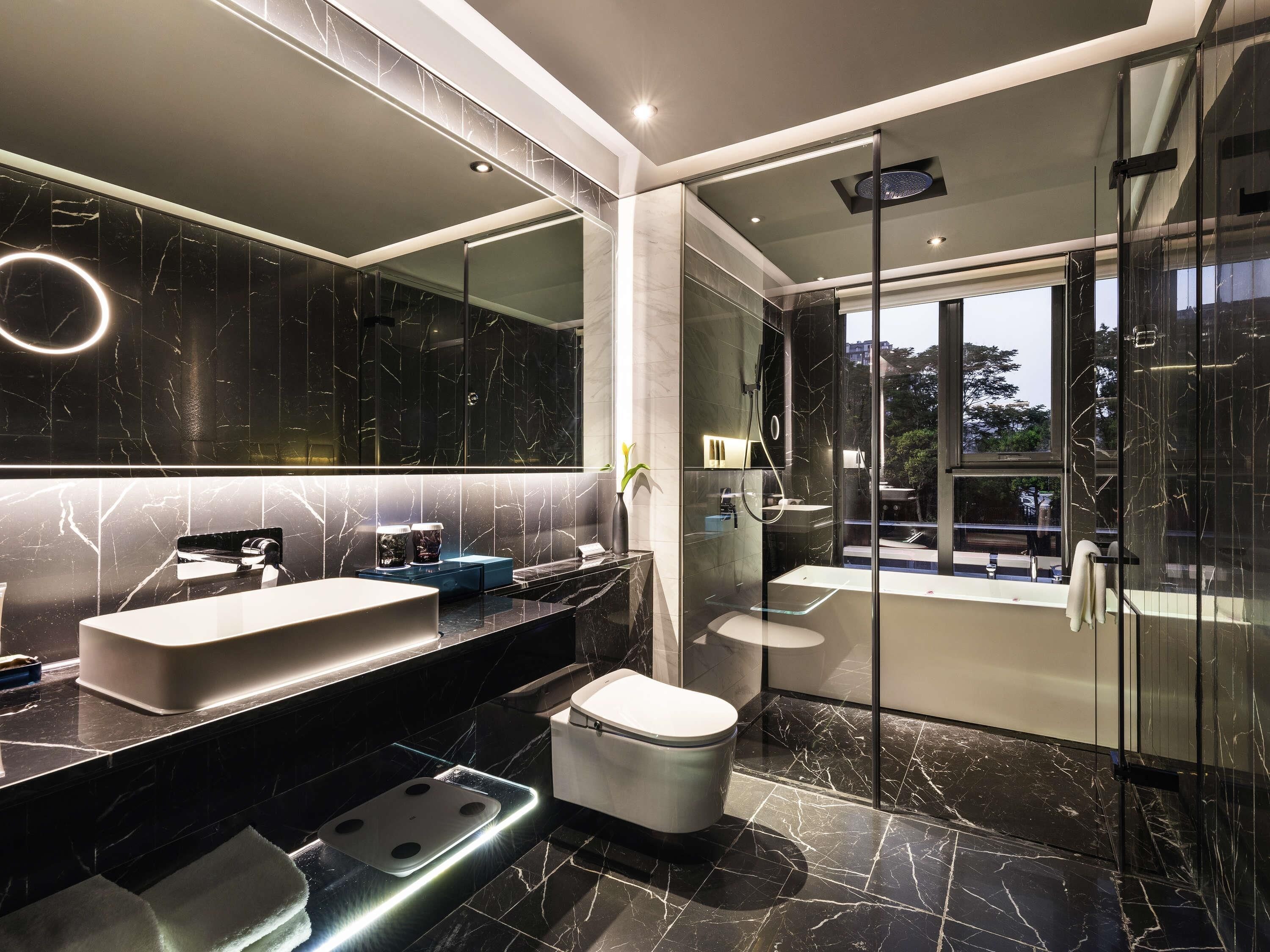 A modern bathroom with a large mirror, a vanity with a sink, a toilet, and a shower area.