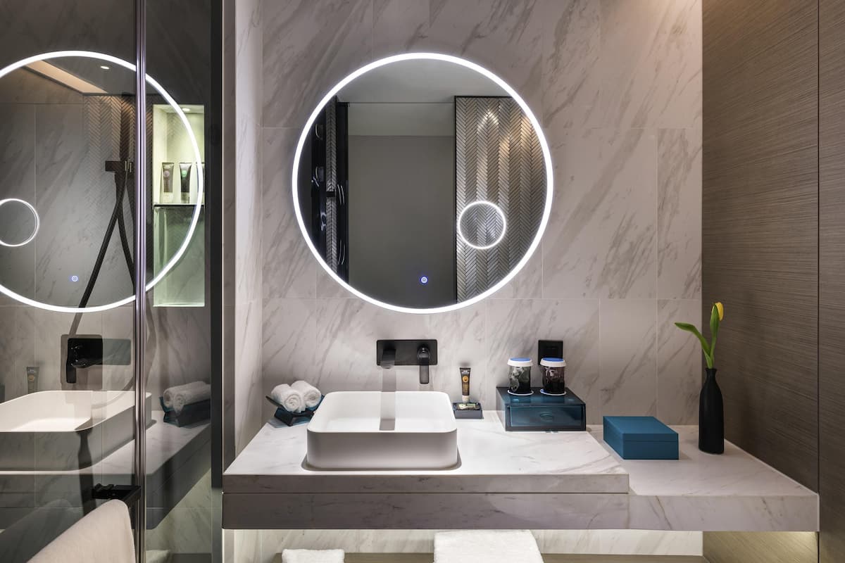 Une salle de bain moderne avec un grand miroir, un lavabo et une douche.