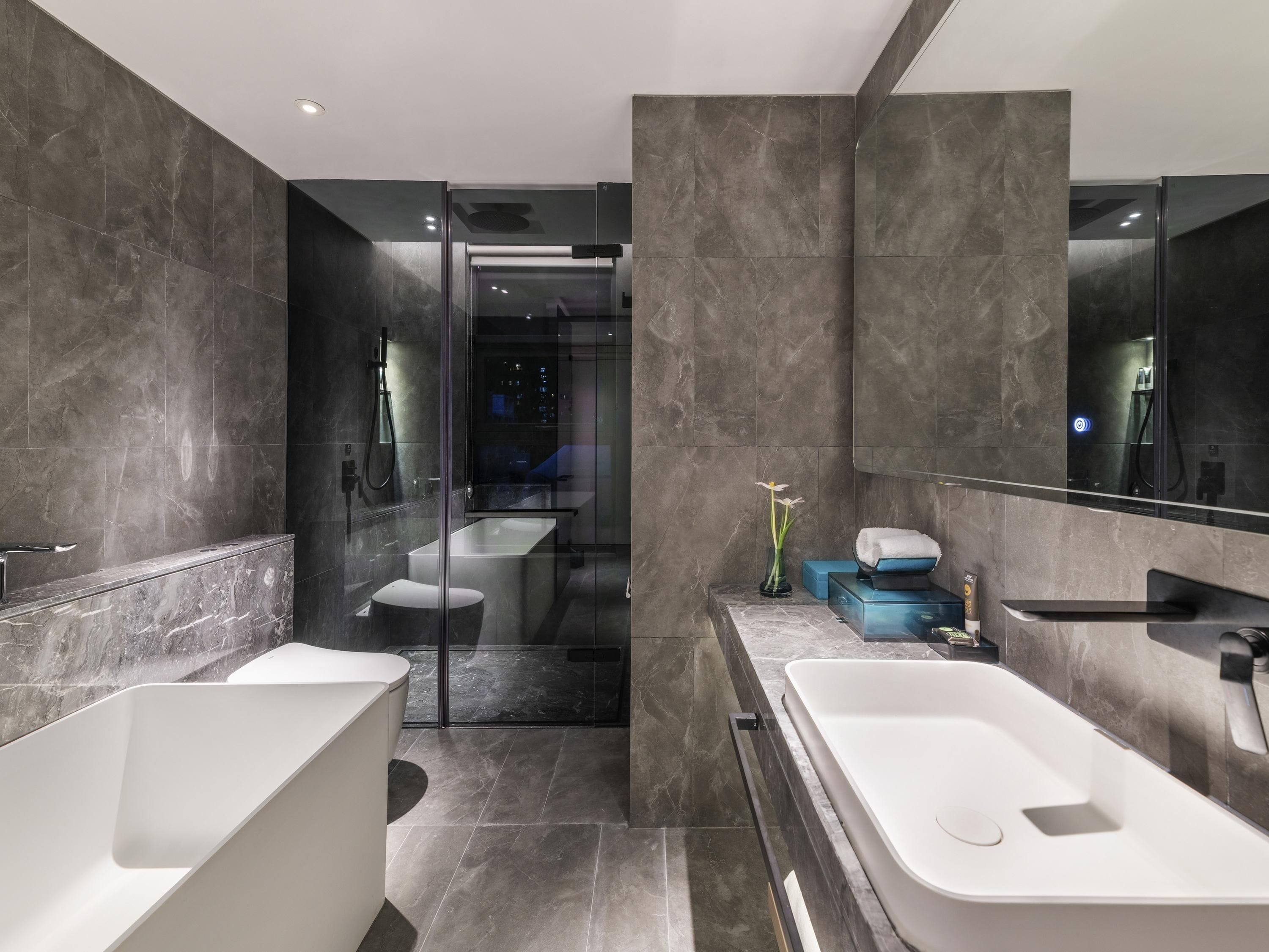 A modern bathroom with a glass shower enclosure, a large bathtub, and a separate toilet area.