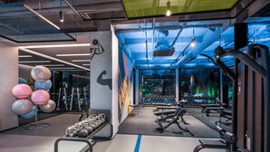 Une salle de sport moderne équipée de divers appareils d’exercice, dotée d’un mur miroir et d’une bande bleue sur le sol.