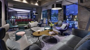 Un espace lounge moderne, doté de sièges confortables, d’un bar et offrant une vue sur le paysage urbain.