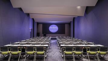 A conference room with rows of tables and chairs, a large screen at the front, and a modern design.
