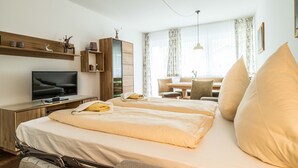 Een hotelkamer met twee bedden, een televisie, een bureau en een raam met gordijnen.
