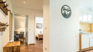 Een moderne keuken met witte kasten, een houten aanrechtblad en een klok aan de muur.