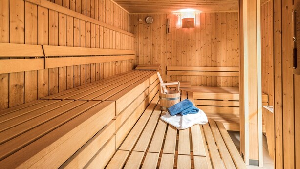 Eine Holzsauna mit Bänken und einem Eimer.