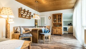 Una habitación acogedora con techo de madera, un sofá, una mesa de comedor y una zona de cocina.