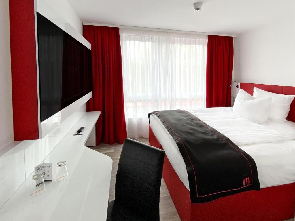 Una habitación de hotel con una cama, televisión, escritorio y una silla.