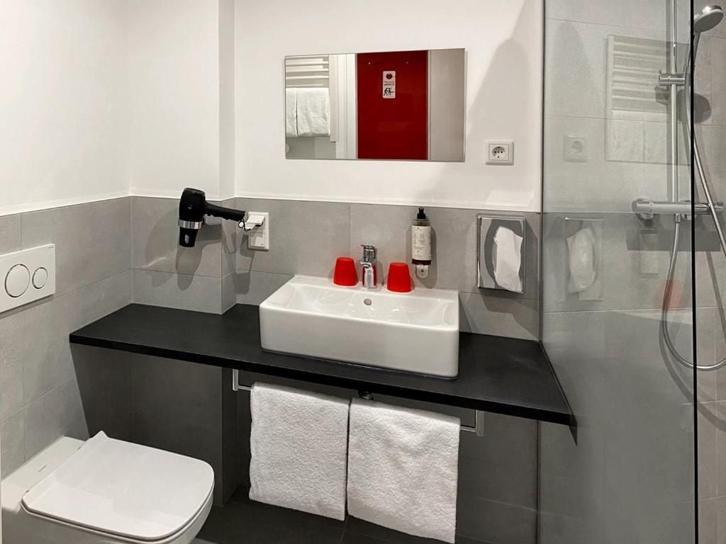 A modern bathroom with a black countertop, white sink, and a glass shower enclosure.