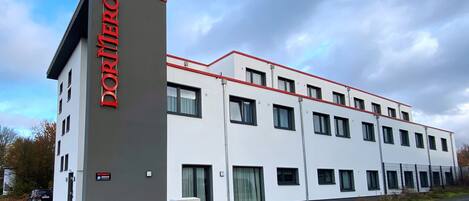 A modern hotel building with a prominent 'DORUMERO' sign on the side.