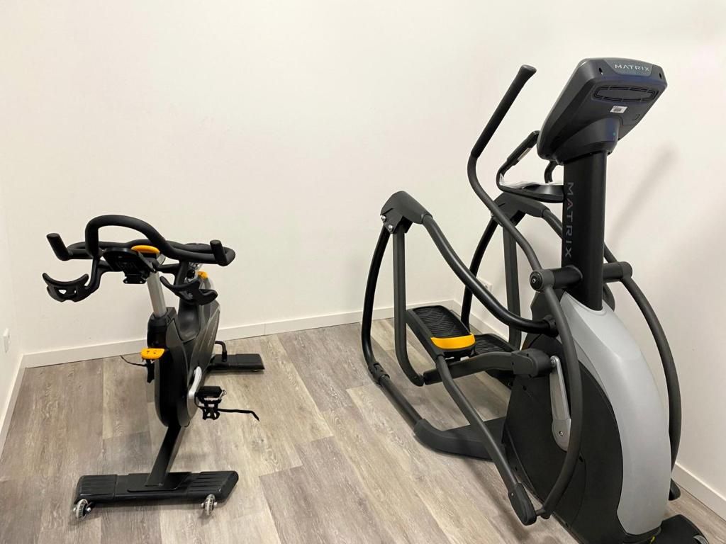 Two stationary bikes in a room with a wooden floor and white walls.