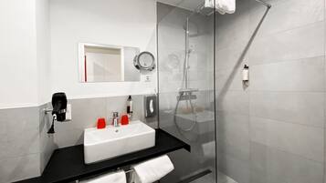 A modern bathroom with a glass-enclosed shower, a white sink, and a black countertop.