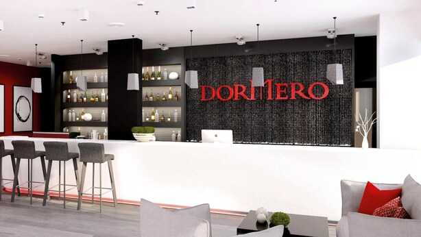 Un área de bar moderna con fondo negro y el nombre 'DORI MERO' en letras rojas. Se observan taburetes de bar y una barra blanca.