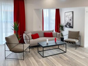 A modern living room with a sofa, two armchairs, a coffee table, and two potted plants. - Dormero Hotel Darmstadt (Darmstadt)