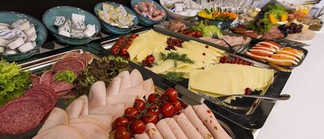 A buffet with various food items including meats, cheeses, and vegetables.