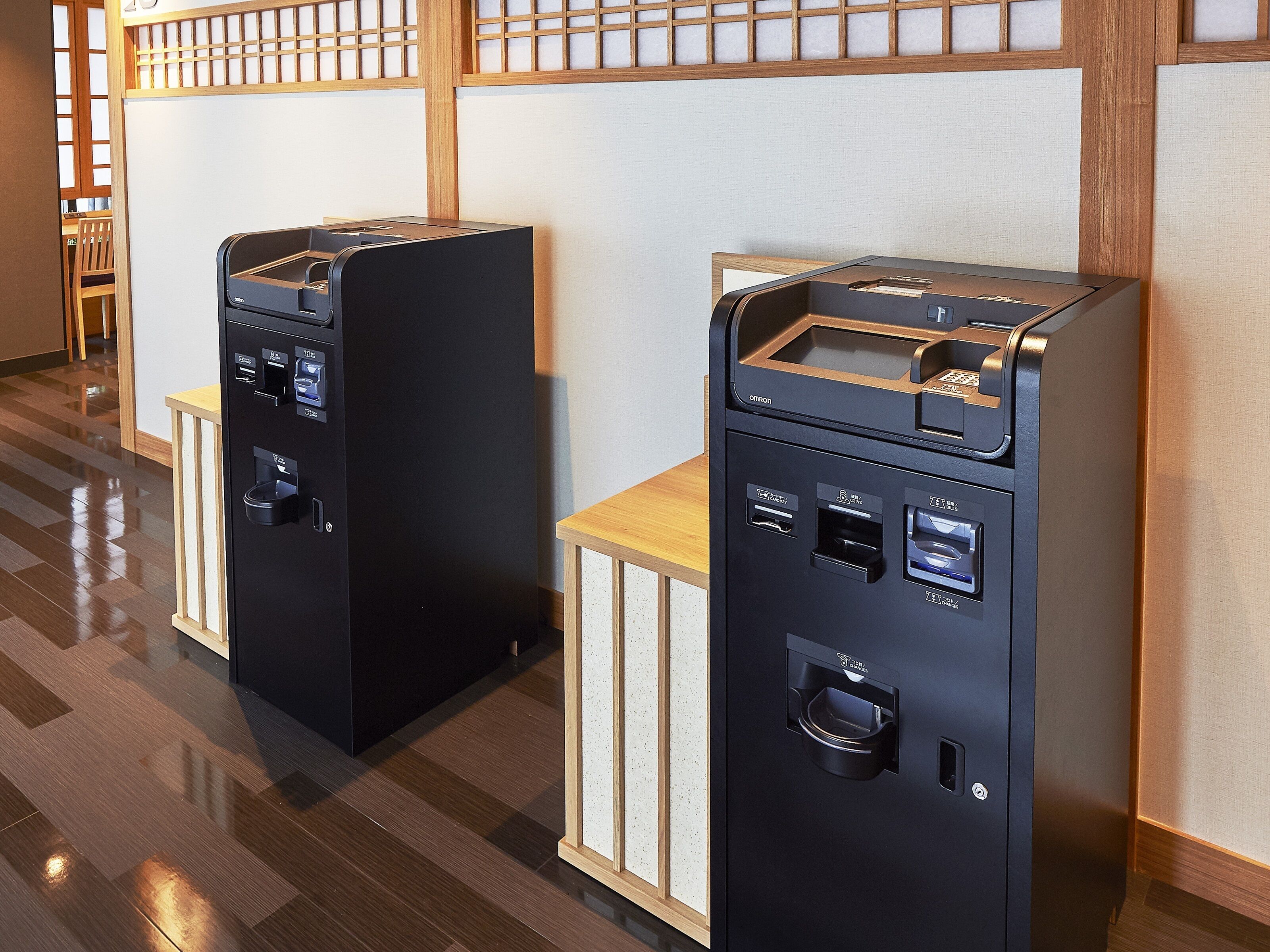 Two self-service beverage dispensers in a modern hotel lobby with wooden flooring and a traditional Japanese-style partition.