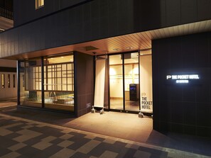 Een moderne hotelentree met glazen deuren, een zichtbaar receptiebalie en een bord met de naam "The Pocket Hotel by SOTETSU".
