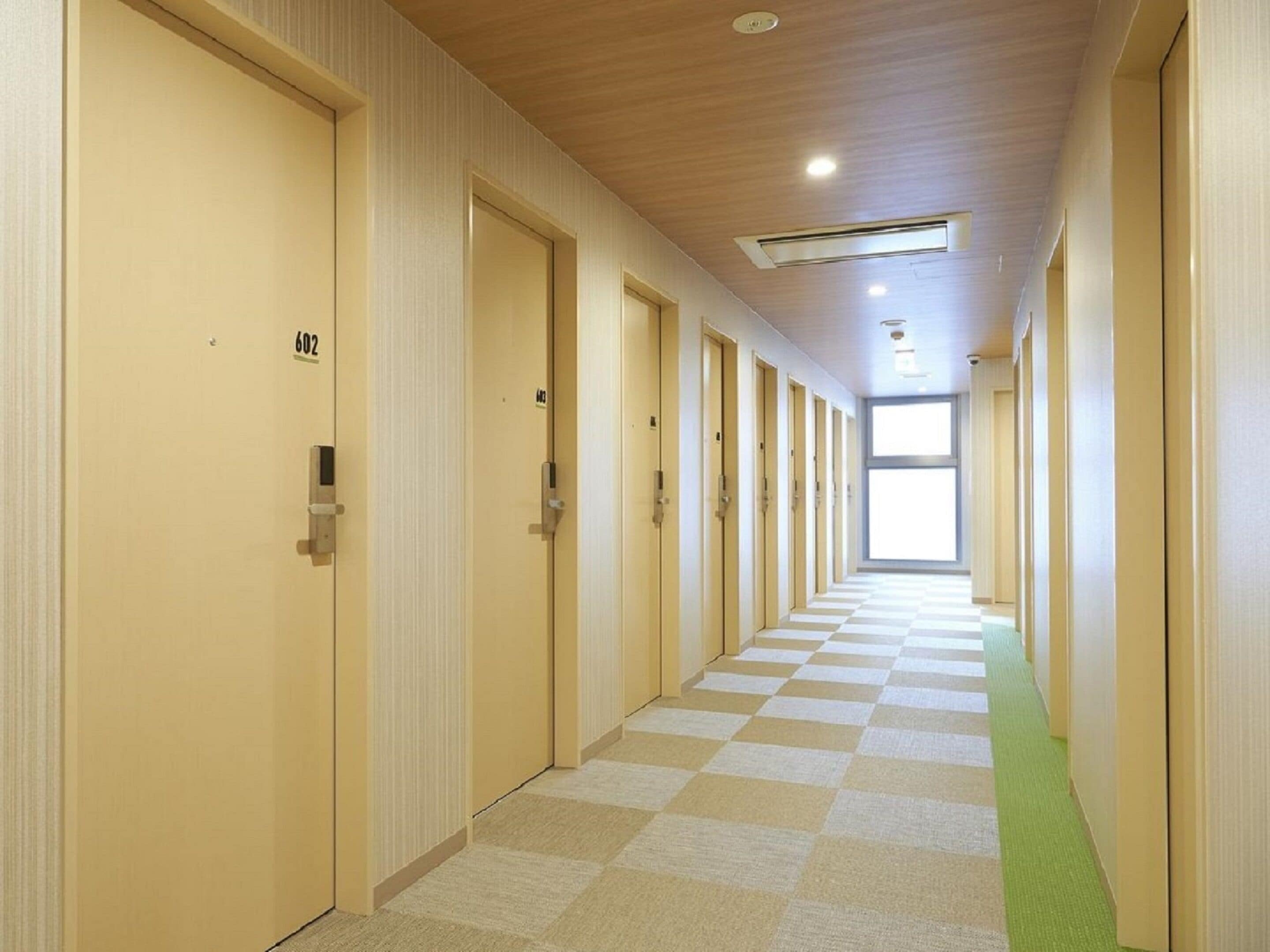 A hotel corridor with checkered flooring, wooden ceiling, and doors numbered 602 and 603.