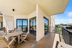 Enjoy the ocean view from this balcony with a table and chairs.