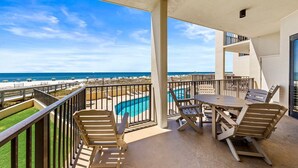 Un balcon avec une piscine, du mobilier d’extérieur et une vue sur la plage et l’océan.
