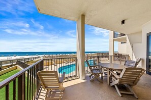 Enjoy the ocean view from this balcony with a table and chairs.