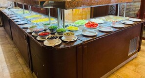 Un mostrador de buffet con diversos alimentos exhibidos en recipientes transparentes.