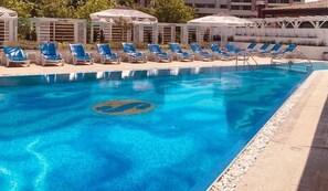 Una piscina con sillones de baño y sombrillas.