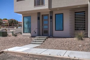 A modern two-story building with a flat roof, a front door, and a set of concrete steps leading to the entrance. - The Lofts #38 | Townhome Pool Resort (Saint George)