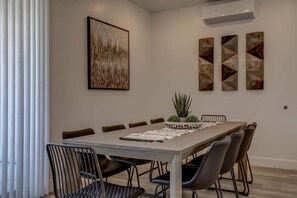 A dining area with a long table, six chairs, and a potted plant. - The Lofts #38 | Townhome Pool Resort (Saint George)