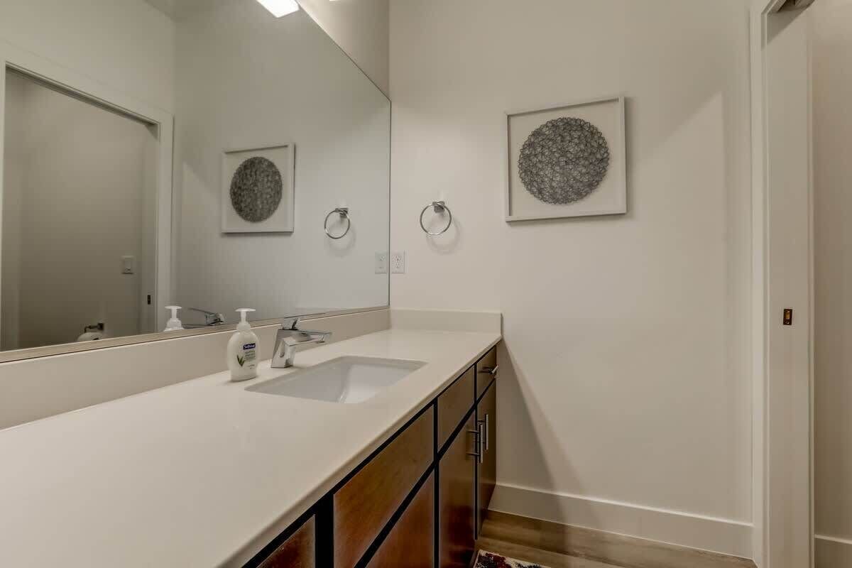A bathroom with a large mirror, two sinks, and artwork on the walls.