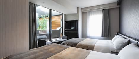 A modern hotel room with two beds, a flat-screen TV, and a view of the outdoors.