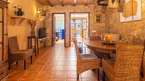 Un coin repas accueillant avec des chaises en osier, une table en bois et des murs en pierre.