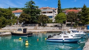 Un porto turistico con barche ormeggiate, un muro in pietra e edifici con tetti rossi sullo sfondo.