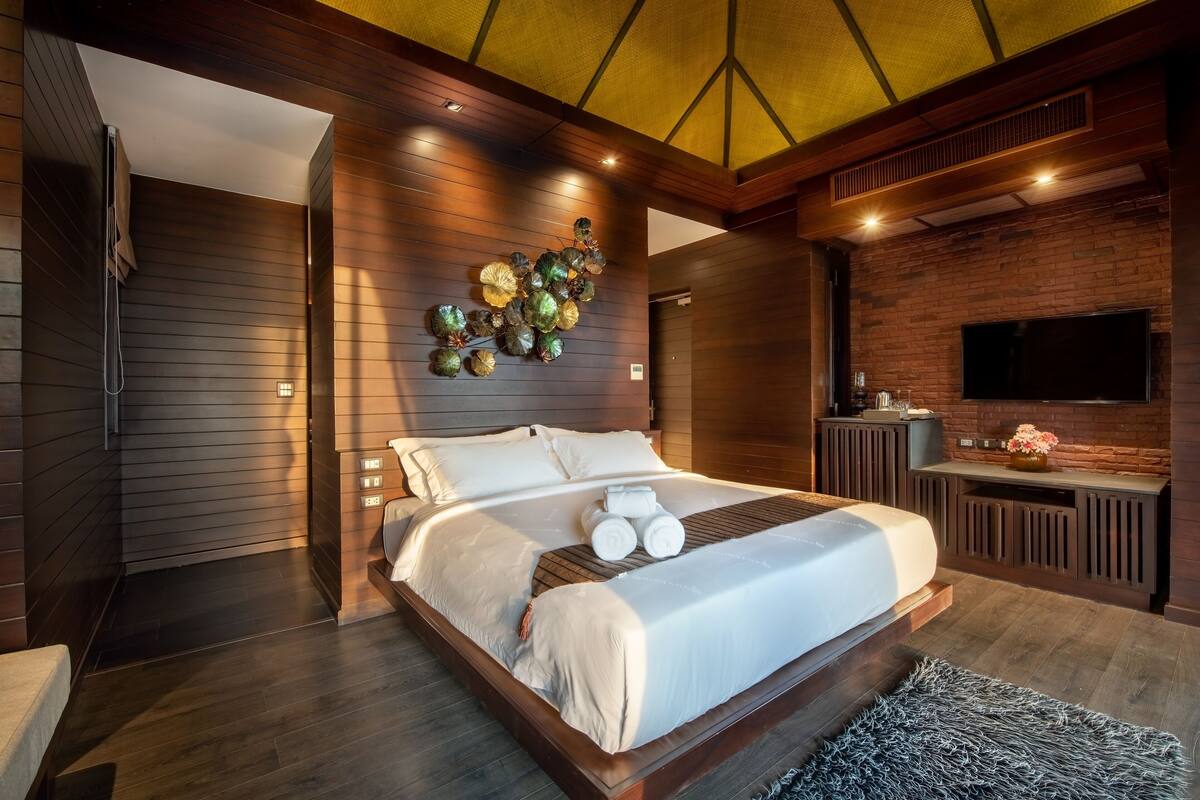 A modern bedroom with a large bed, a TV, and a decorative wall piece.