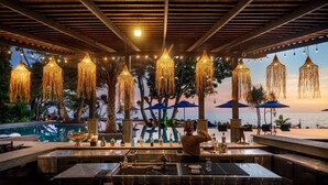An outdoor bar area with a pool, bar stools, and hanging lights. - Nirvana  Beach Resort (Ko Lanta)