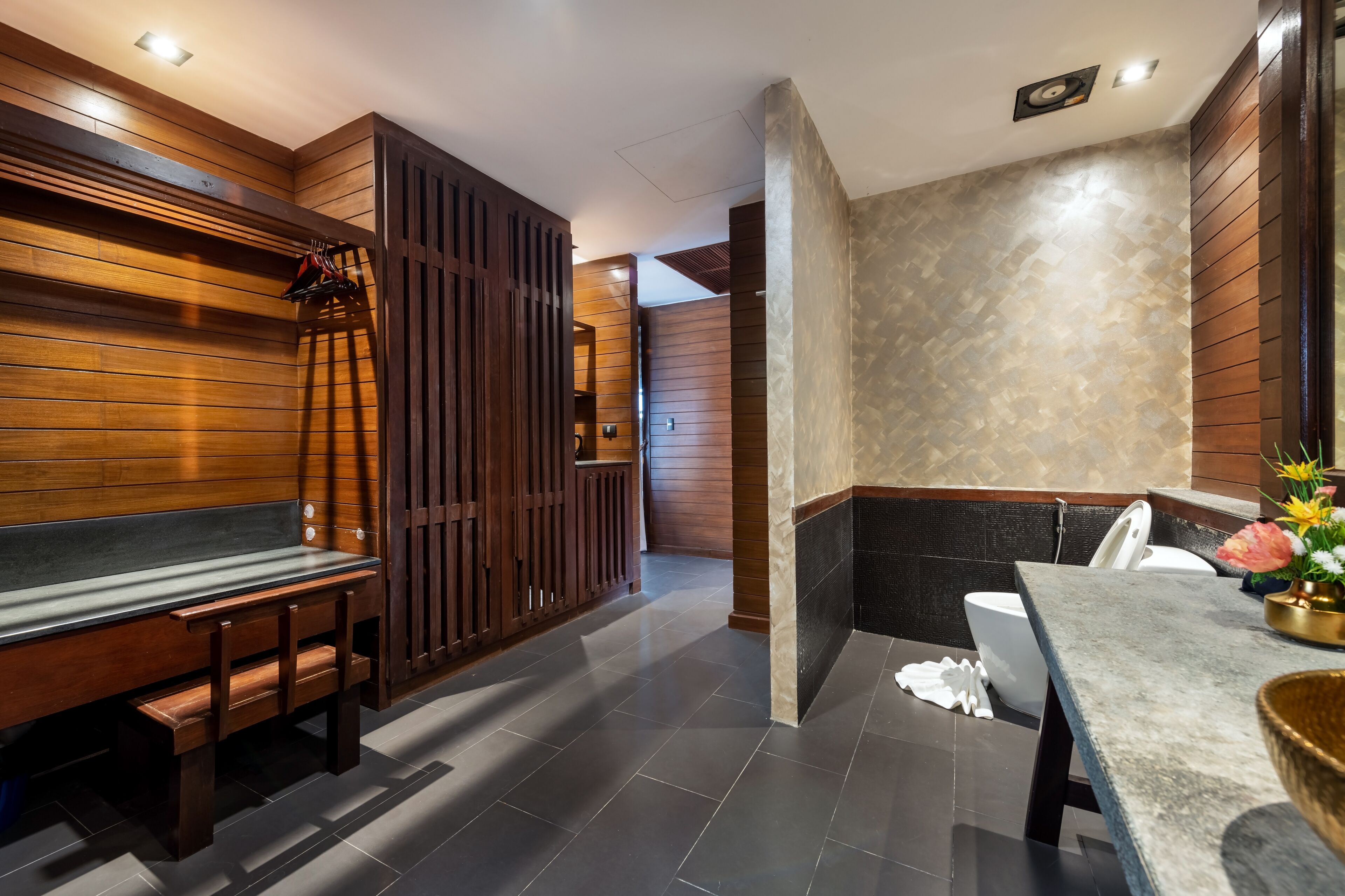 A modern bathroom with a wooden bench, a toilet, and a sink area.