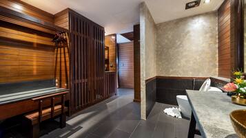 A modern bathroom with a wooden bench, a toilet, and a sink area.