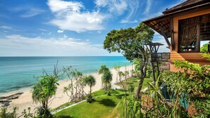 A beachfront property with a large window overlooking the ocean, a covered patio, and a well-maintained lawn. - Nirvana  Beach Resort (Ko Lanta)