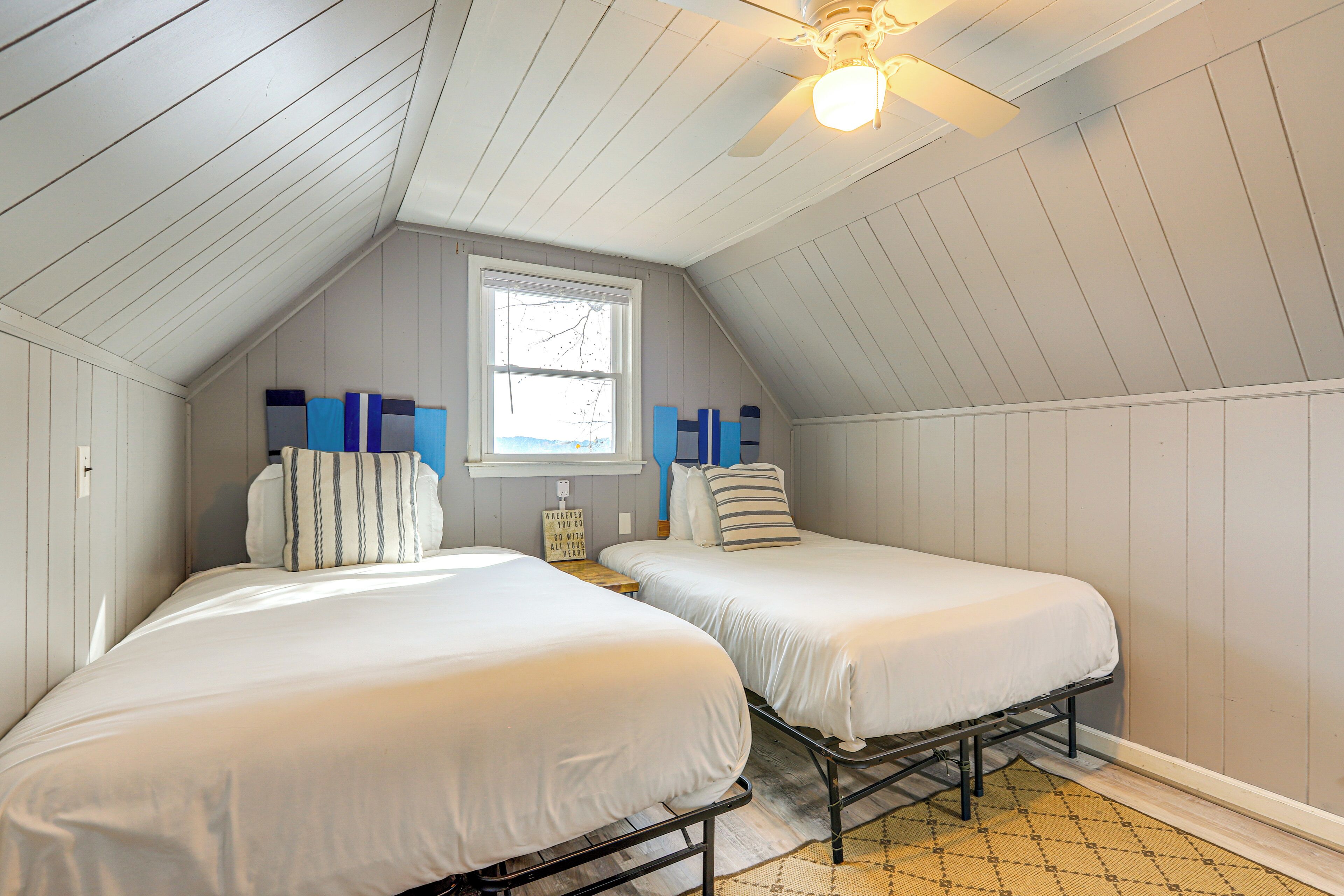 A bedroom with two beds, a window, and a ceiling fan.