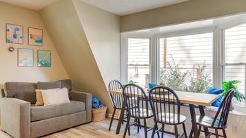 Un salon confortable avec un canapé, une table à manger et des chaises, ainsi que des œuvres d’art accrochées au mur.