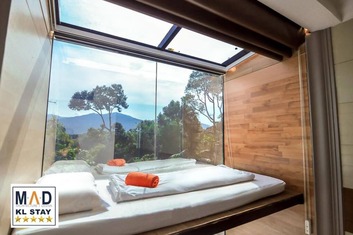 Ein modernes Hotelzimmer mit einem großen Oberlicht, Holzvertäfelung und Blick auf Bäume und Berge.