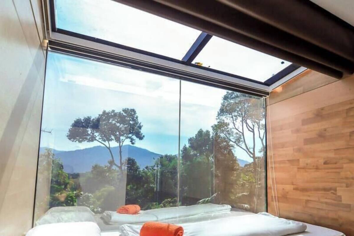 Ein Schlafzimmer mit Dachfenster, Holzvertäfelung und einem Bett mit Kissen.