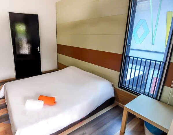 A hotel room with a bed, a desk, and a window with a view.