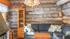 A cozy log cabin interior with a wooden cabinet, a sofa, and a small table. - Aihkelo by Interhome (Sodankylä)