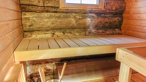A wooden cabin interior with a bench, a window, and a metal bucket with a ladle. - Aihkelo by Interhome (Sodankylä)