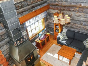 L’intérieur chaleureux d’un chalet en bois comprend une cheminée en pierre, un canapé, une table basse en bois et un coin repas agrémenté d’un lustre.